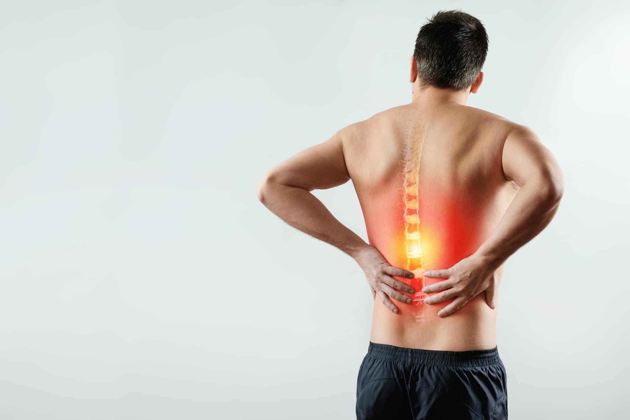 Man holds his painful back in Sugar Land, prior to laser spine surgery