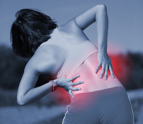 Woman in Sugar Land, struggling with chronic back pain, holds her back and considers spine surgery