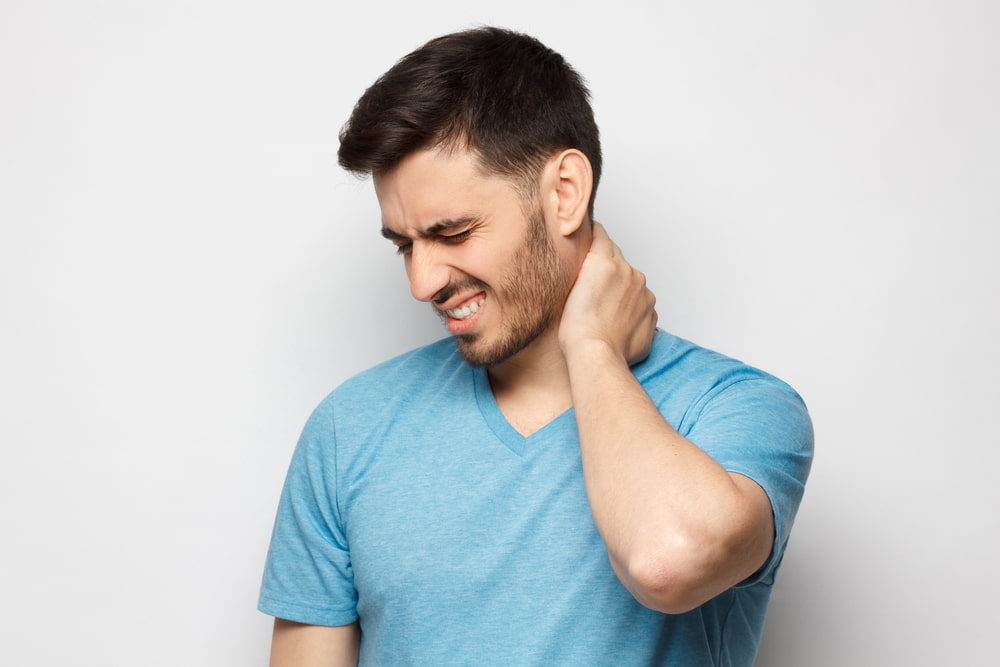 Man in Sugar Land holds his neck in pain due to a herniated disc