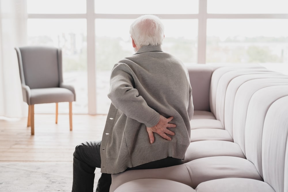 Elderly Sugar Land man clutches his back in pain due to degenerative disc disease