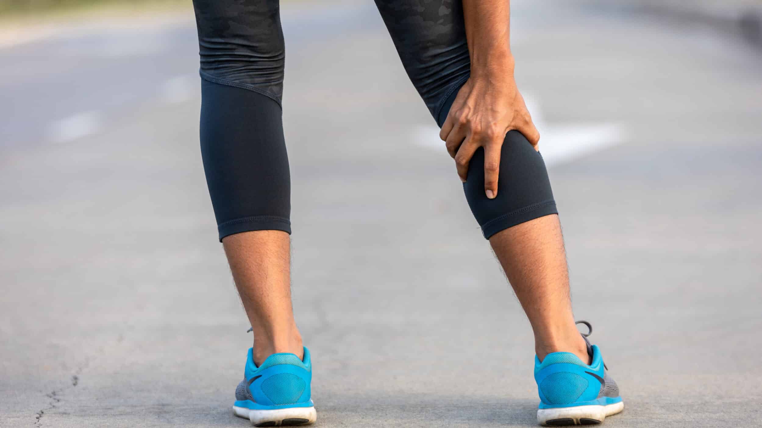 Runner holding calf with leg weakness or pain that may be linked to spine-related nerve symptoms.
