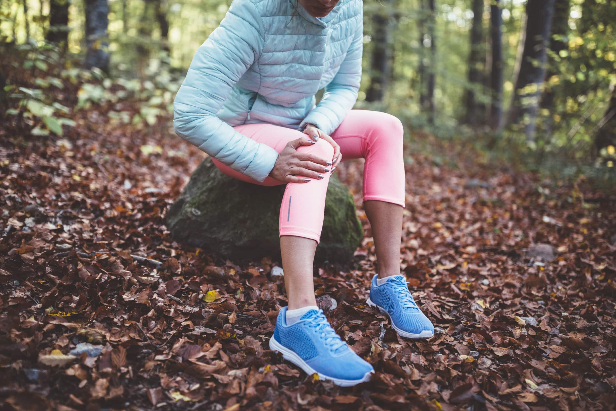 Hiker sitting on a rock with leg pain that may be related to spinal stenosis symptoms while walking.